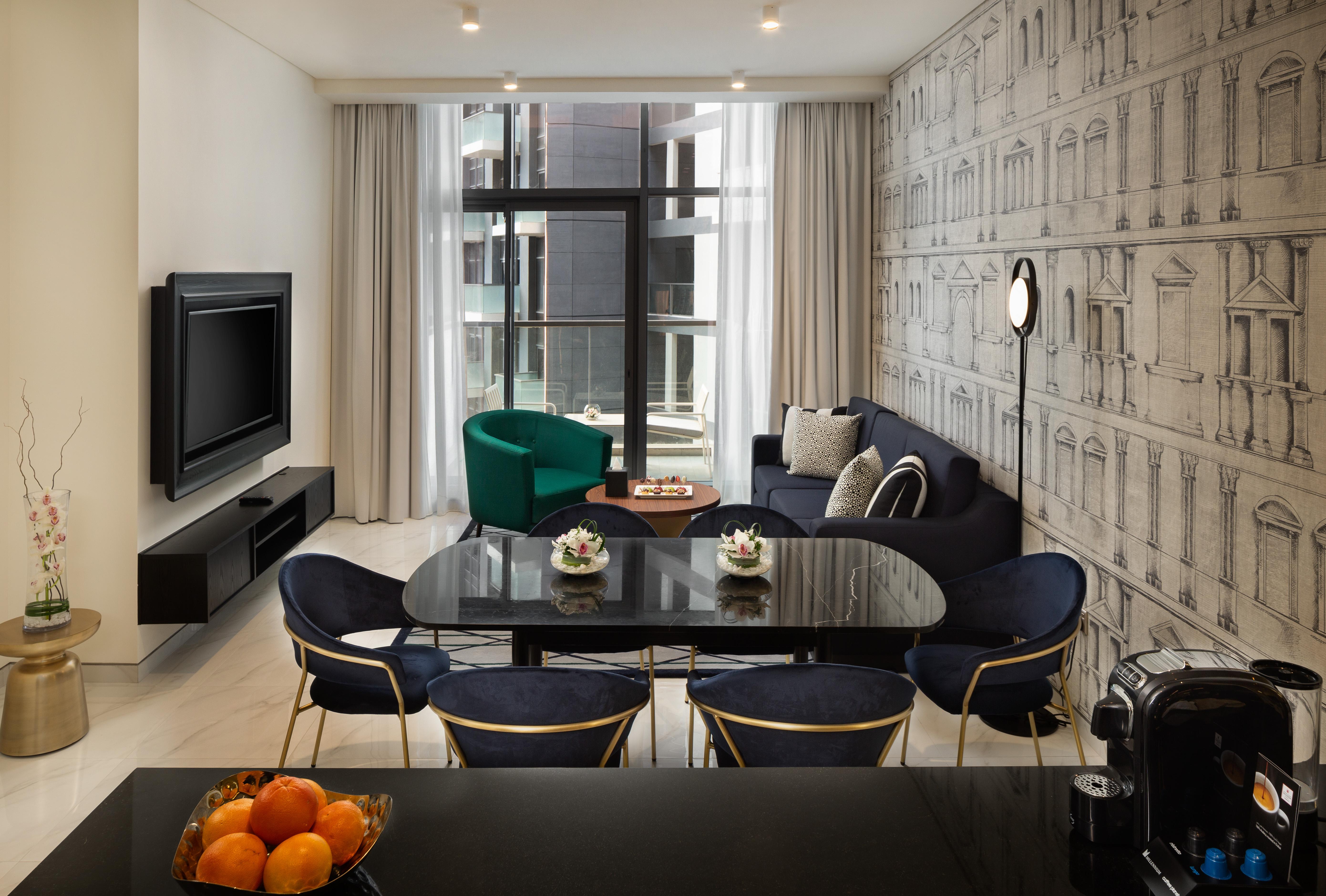 มิลเลนเนียม เอเตรีย บิสซิเนส เบย์ Aparthotel ดูไบ ภายนอก รูปภาพ The photo shows a modern living space that includes a cozy seating area and dining setup. On the left, there is a large television mounted on the wall. The living room features a blue sofa and a green accent chair, creating a stylish contrast. A smal