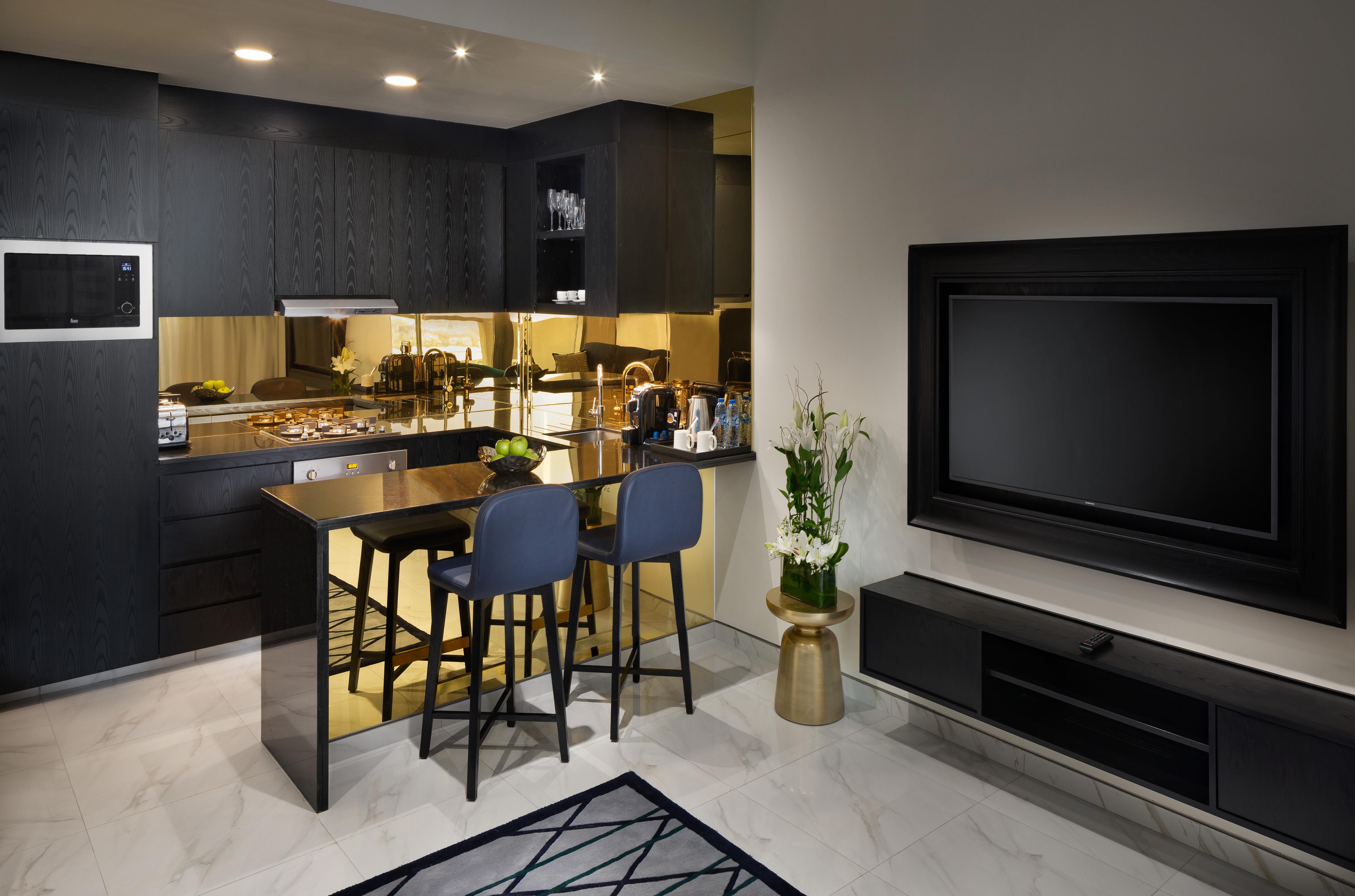 มิลเลนเนียม เอเตรีย บิสซิเนส เบย์ Aparthotel ดูไบ ภายนอก รูปภาพ The photo depicts a modern kitchen and living area. The kitchen features dark cabinetry with a clean design, showcasing various appliances, including a stovetop and possibly an oven. There is a kitchen island with two stools, suggesting a space for c