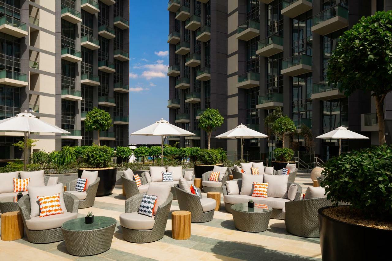มิลเลนเนียม เอเตรีย บิสซิเนส เบย์ Aparthotel ดูไบ ภายนอก รูปภาพ The photo shows a modern outdoor lounge area, featuring several comfortable seating arrangements made of soft, stylish lounge chairs and round tables. The seating is adorned with colorful pillows, adding a pop of color to the neutral tones of the fur